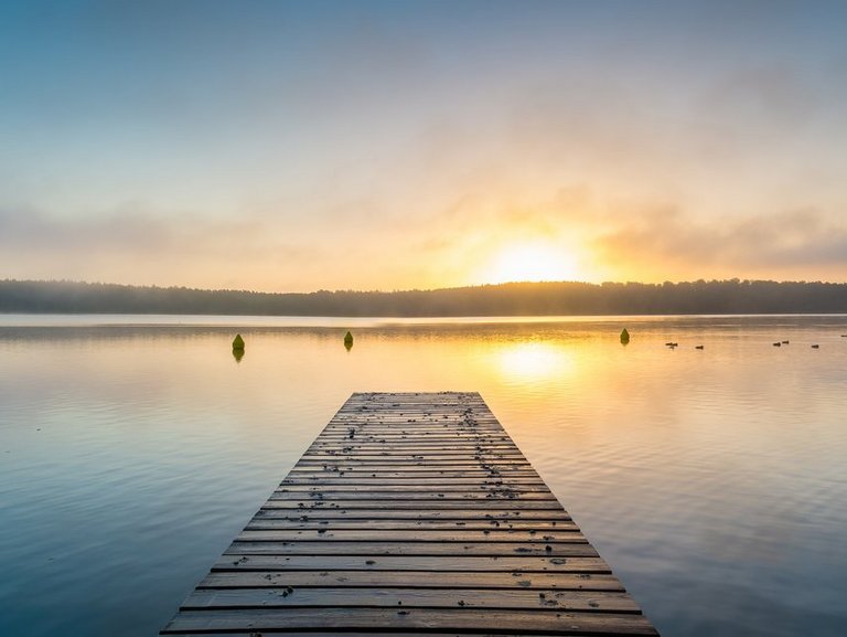 naturbild-seestimmung mit steg-sonnenspiegelung auf dem wasser